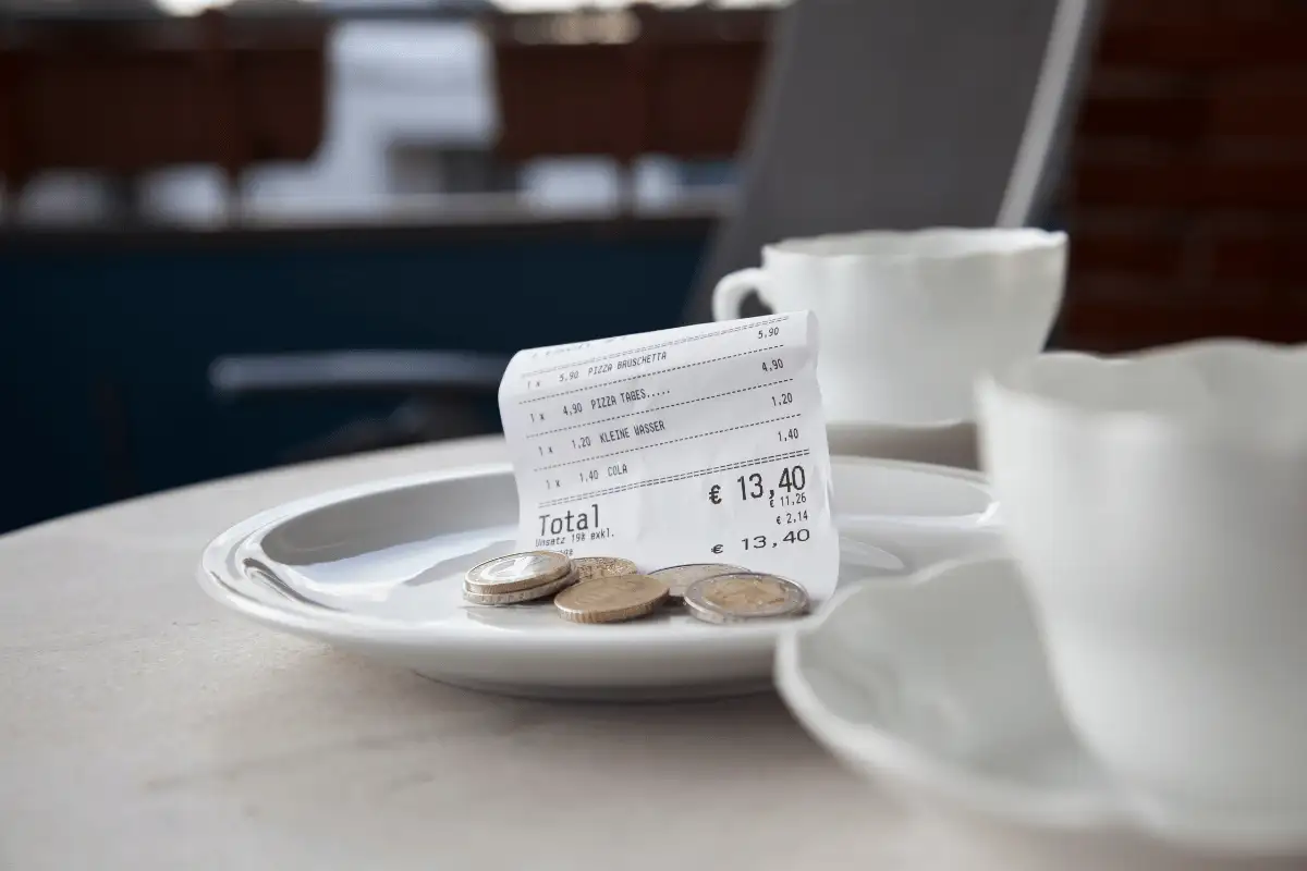 A coffee dish with the bill and some coins on top of it.