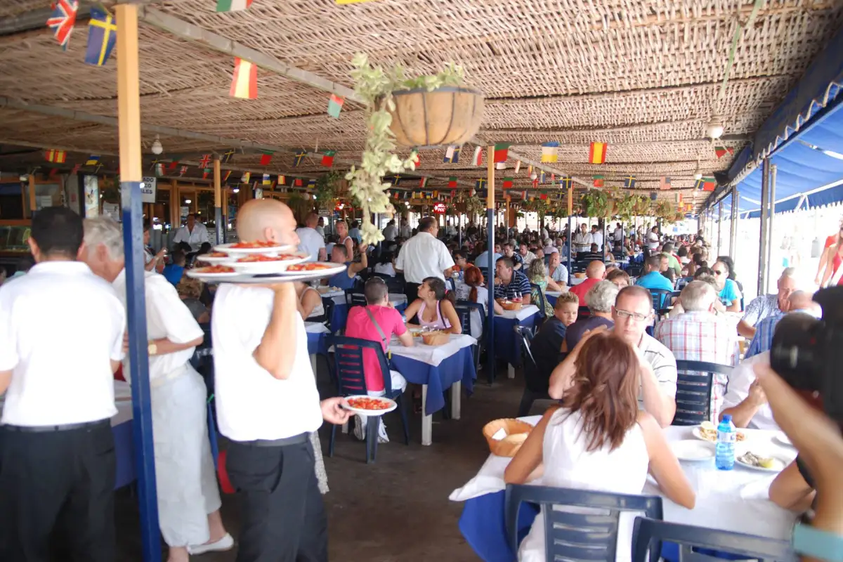 A very busy dining area with waiters carrying food at Chiringuito El Tintero.