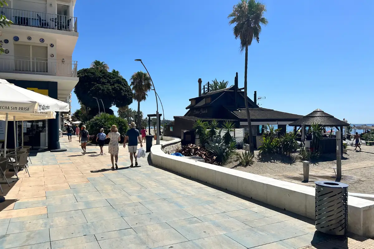 people walking on the promenade in estepona with restraunts on the left and the beach on the right.