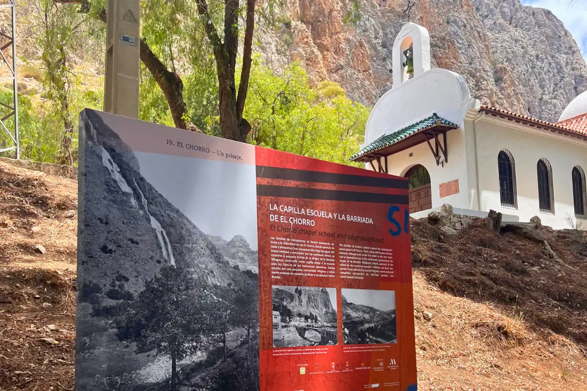 A sign depicting the Caminito del Rey original trail with the registration office behind it.