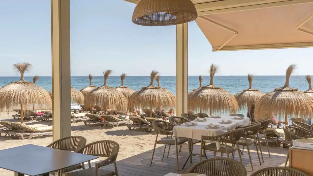 cabanas on the beach with an ocean behind them, viewed from the Oasis Chiringuito in Malaga.