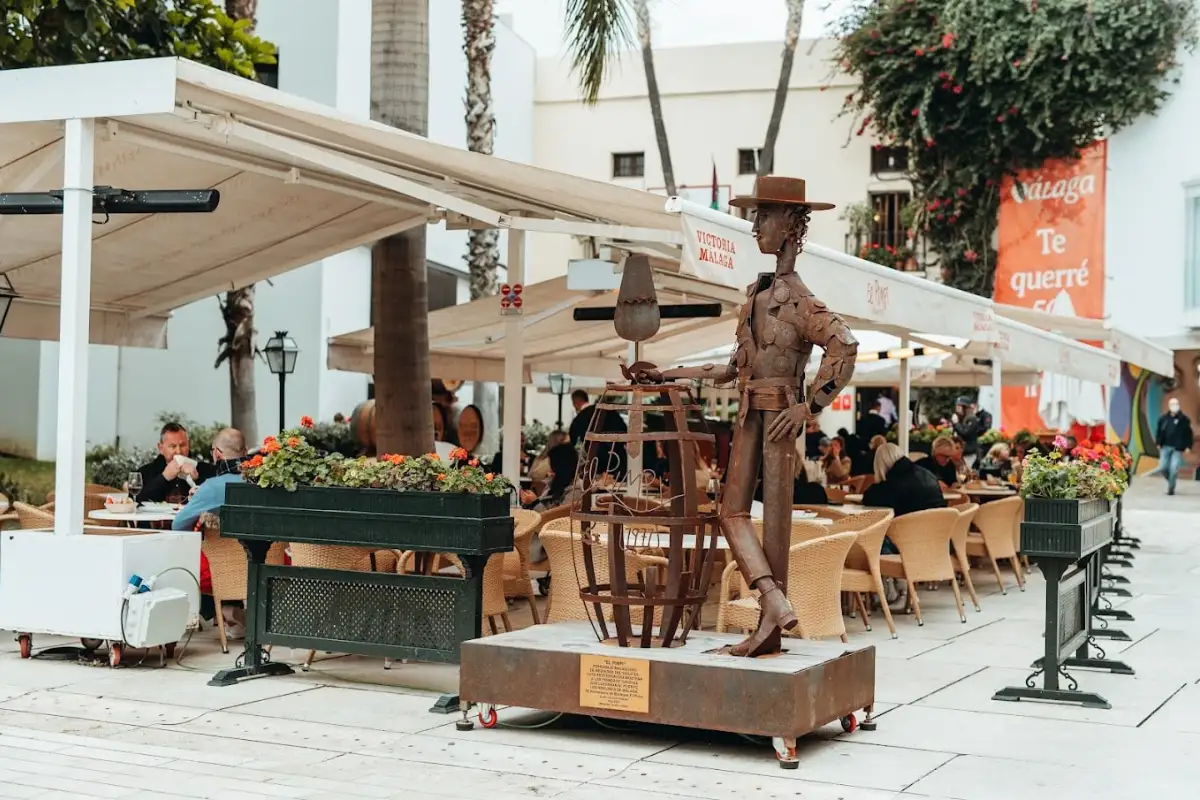 A statue in front of diners eating at restaurant El Pimpi in Malaga.