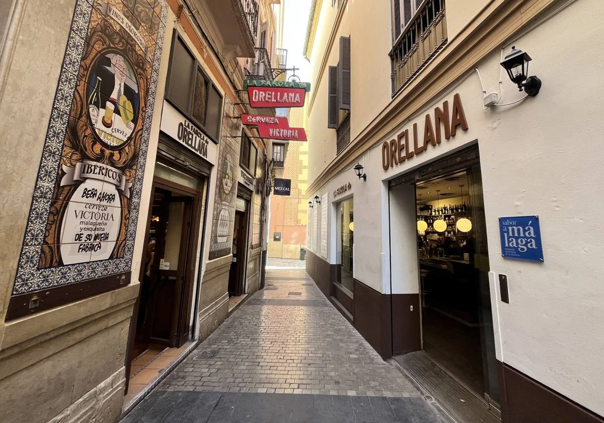 A narrow street view with restaurants on either side in Malaga Old Town.