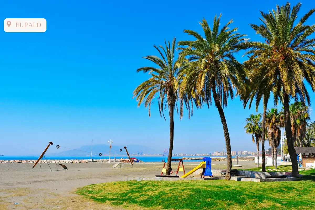 palm trees before a brown sand beach with childrens play area at playa el palo.