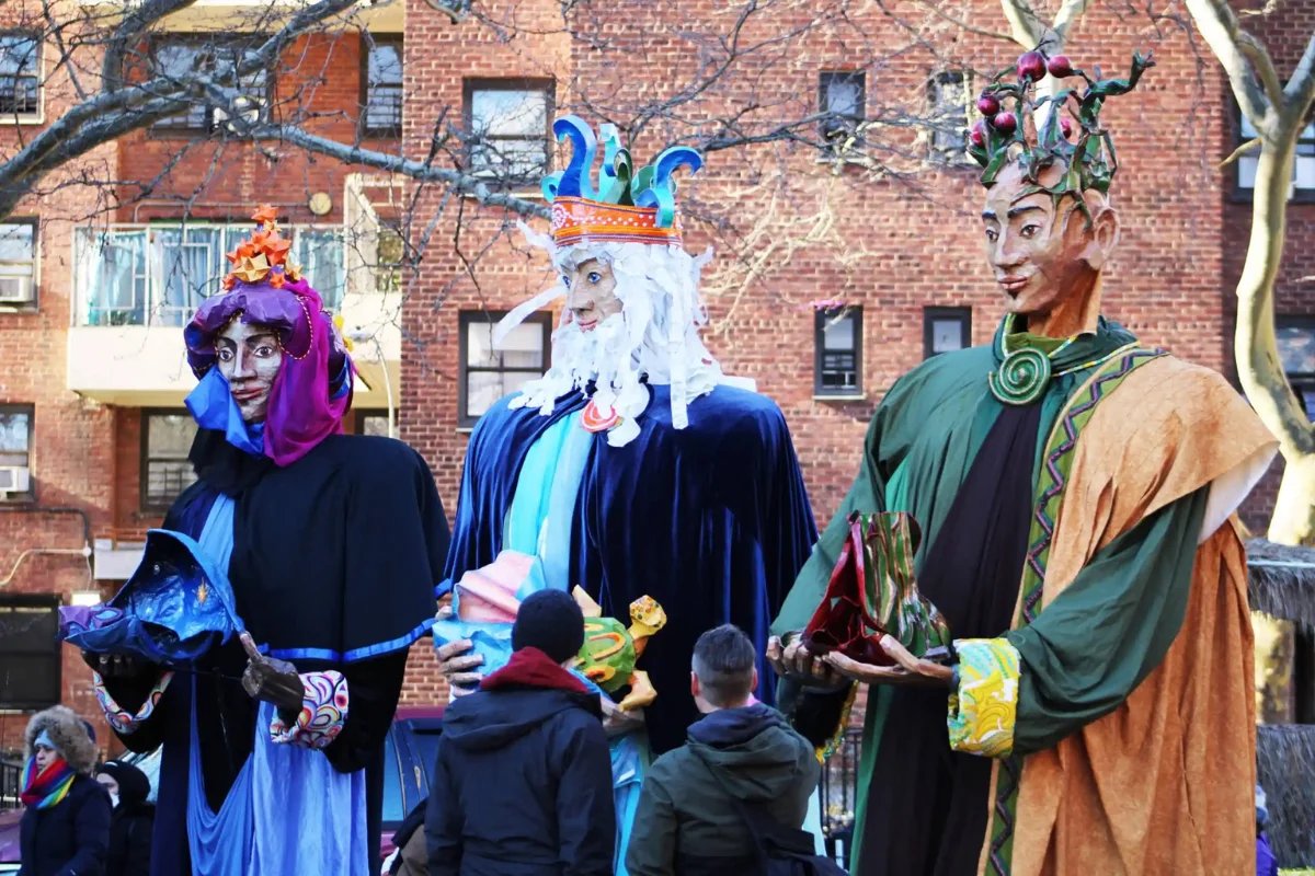 Three sculptures of the three kings are being paraded down a street.
